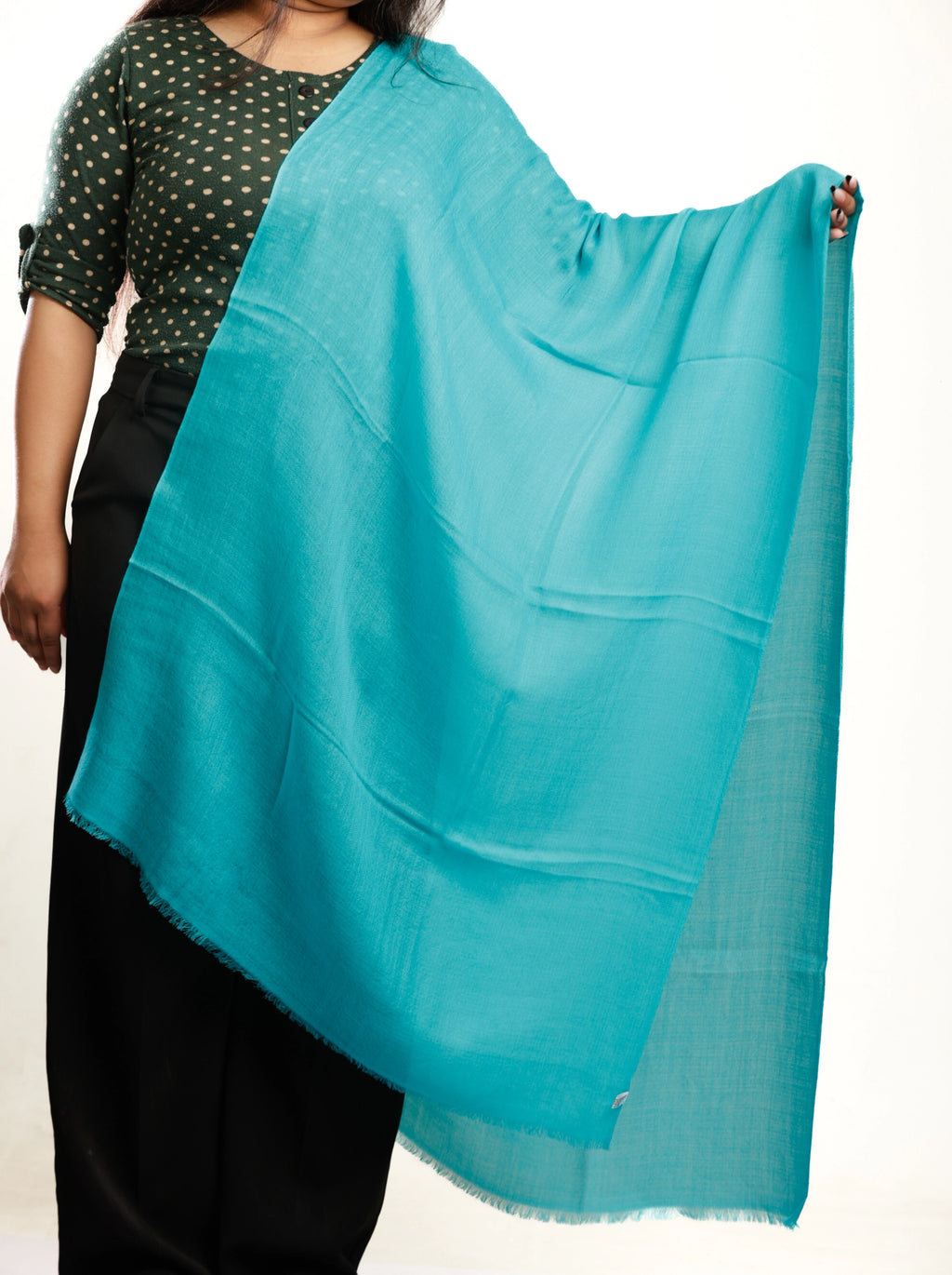 Person wearing a turquoise scarf over their shoulder on a white background