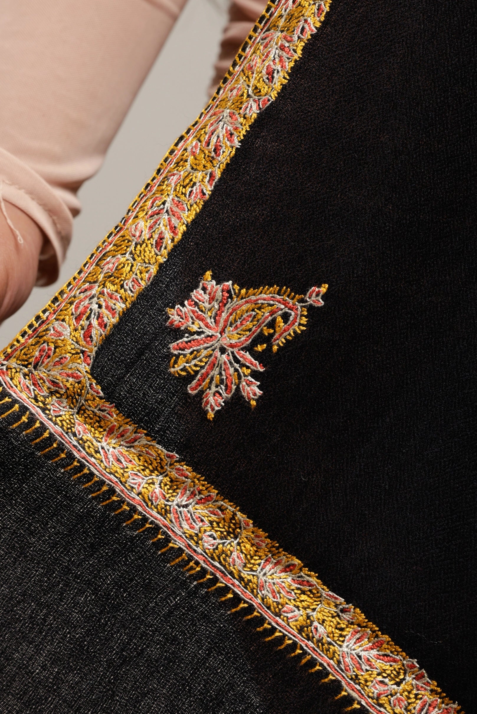 Close-up of black shawl with intricate yellow and red embroidery