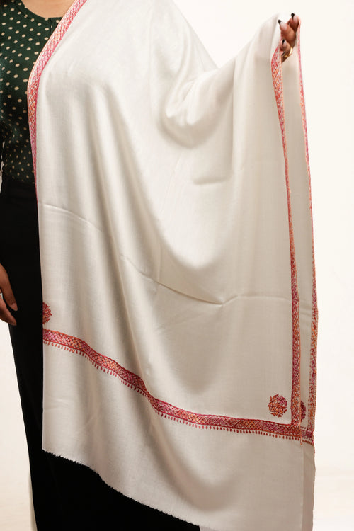 White shawl with red embroidered border held by a person on a white background