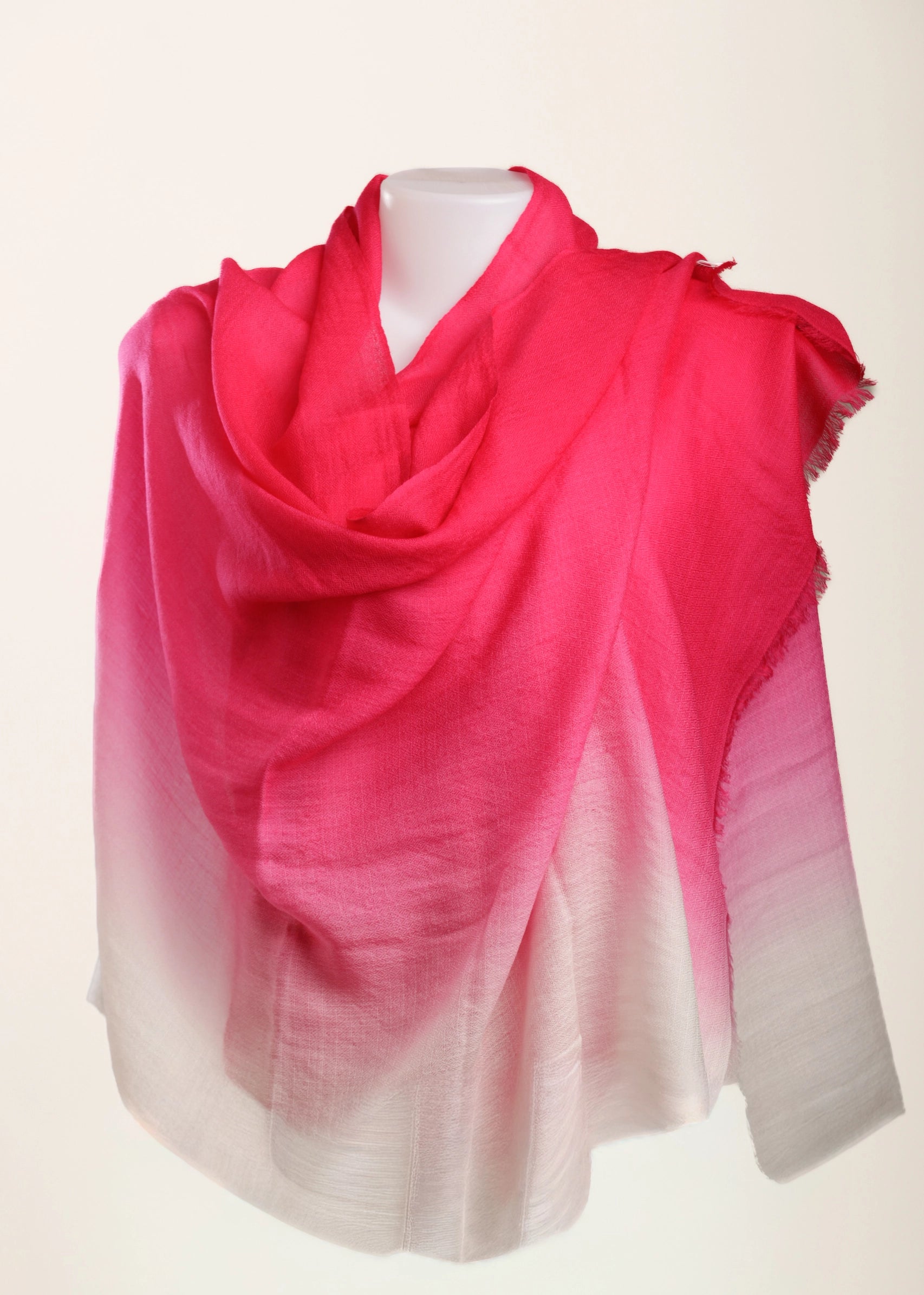 A lightweight draped scarf with a vibrant pink to white ombré gradient, displayed on a white mannequin torso against a plain off-white background.