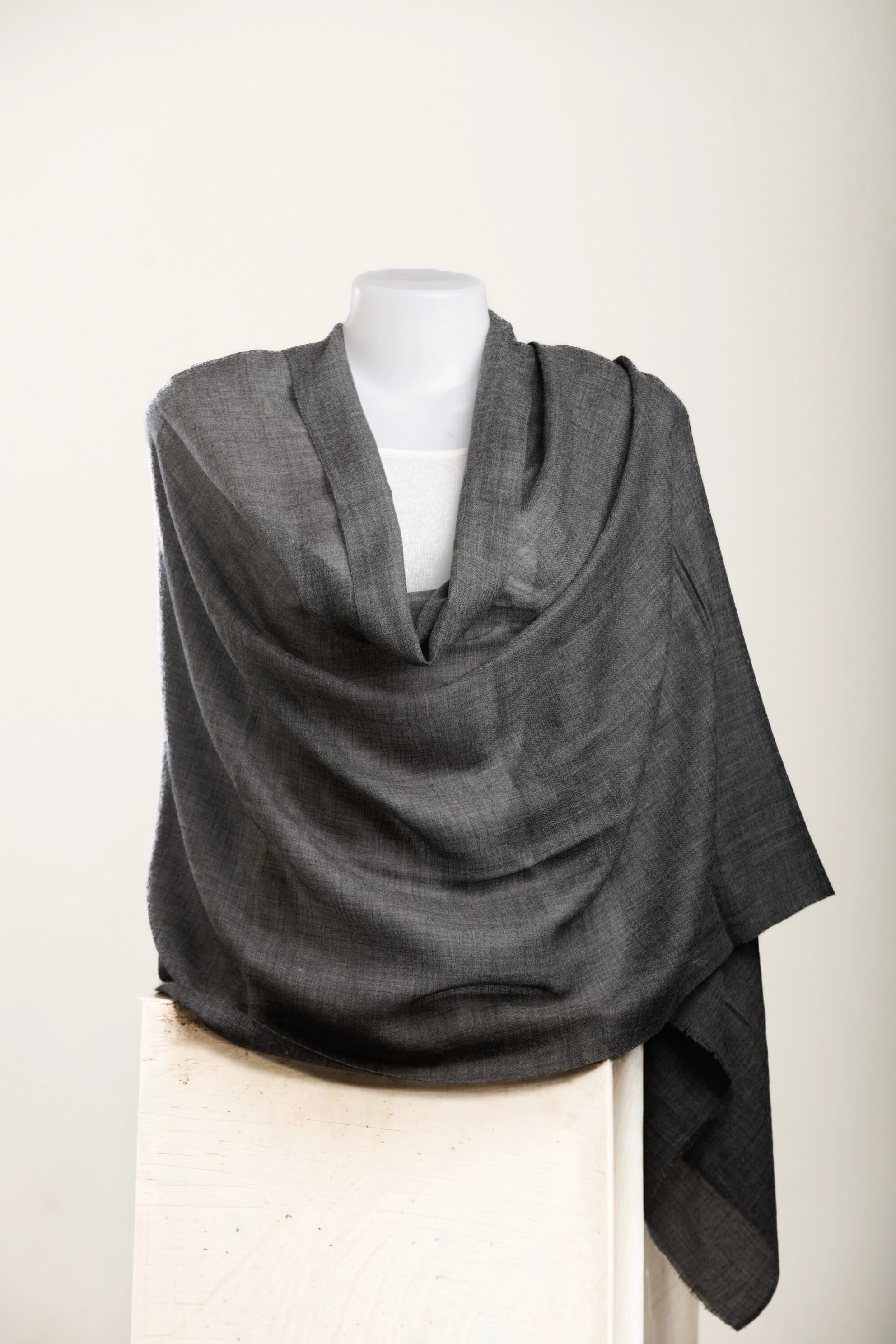 Gray shawl draped over a mannequin on a white background