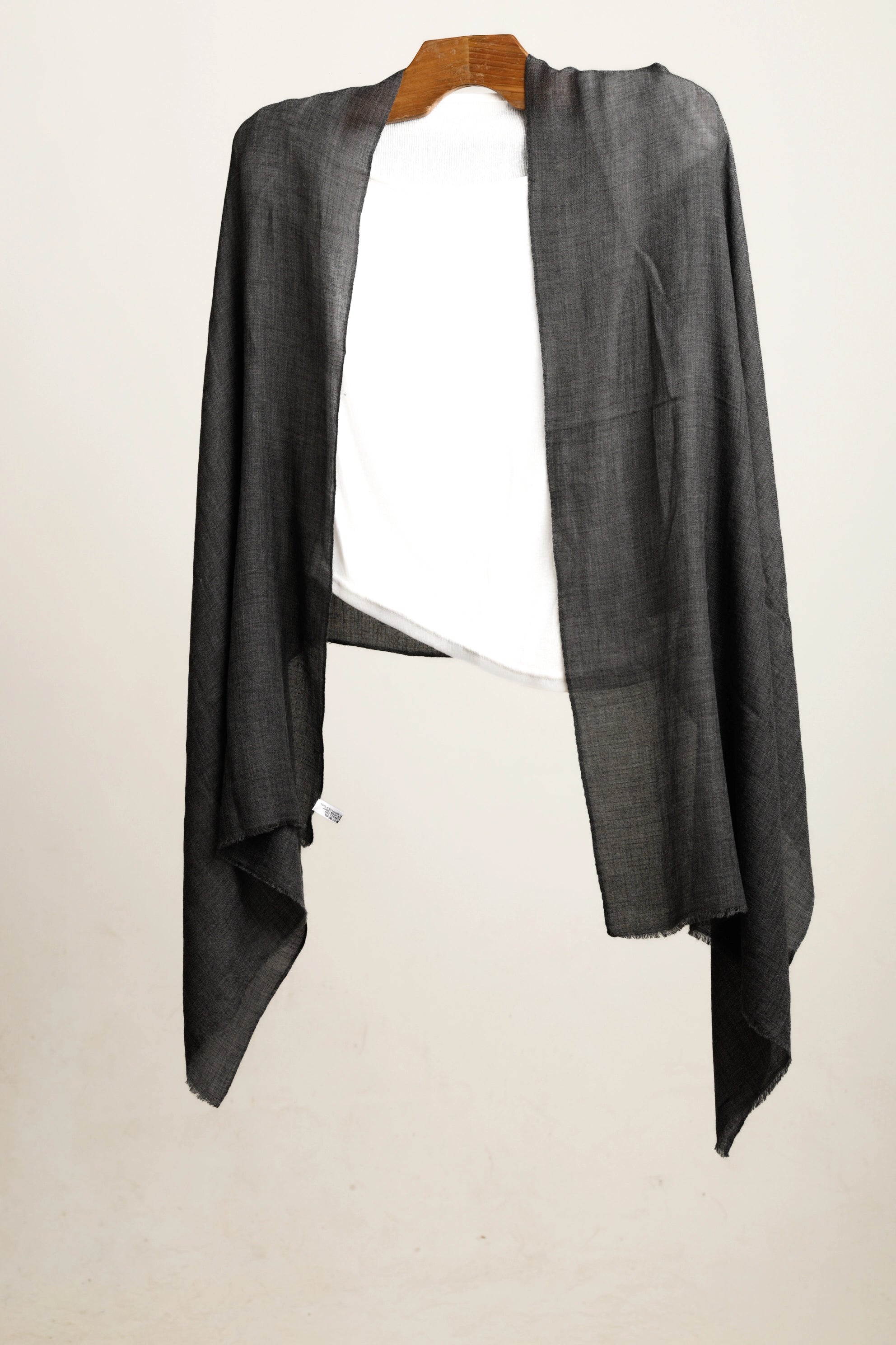 Gray shawl on a wooden hanger layered over a white top against a white background