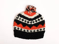 Black and orange knitted hat with a pom-pom on a white background