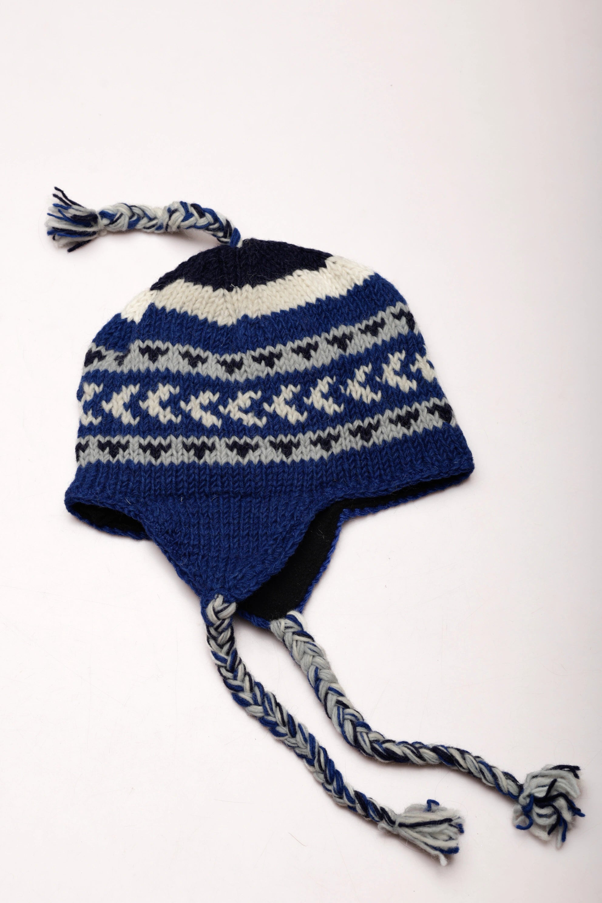 Blue knitted hat with pattern and tassels on a white background