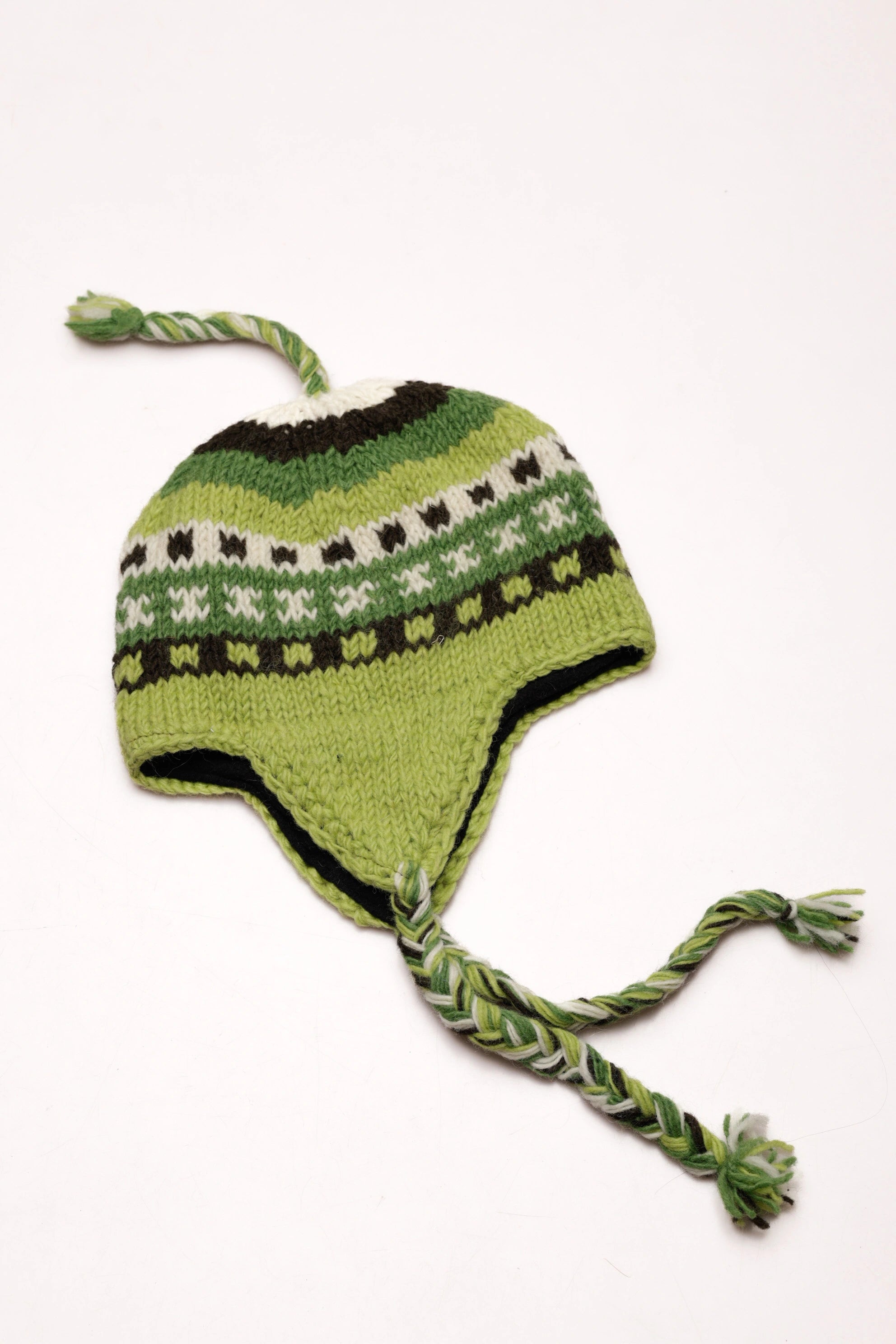 Green knitted hat with braided tassels on a white background