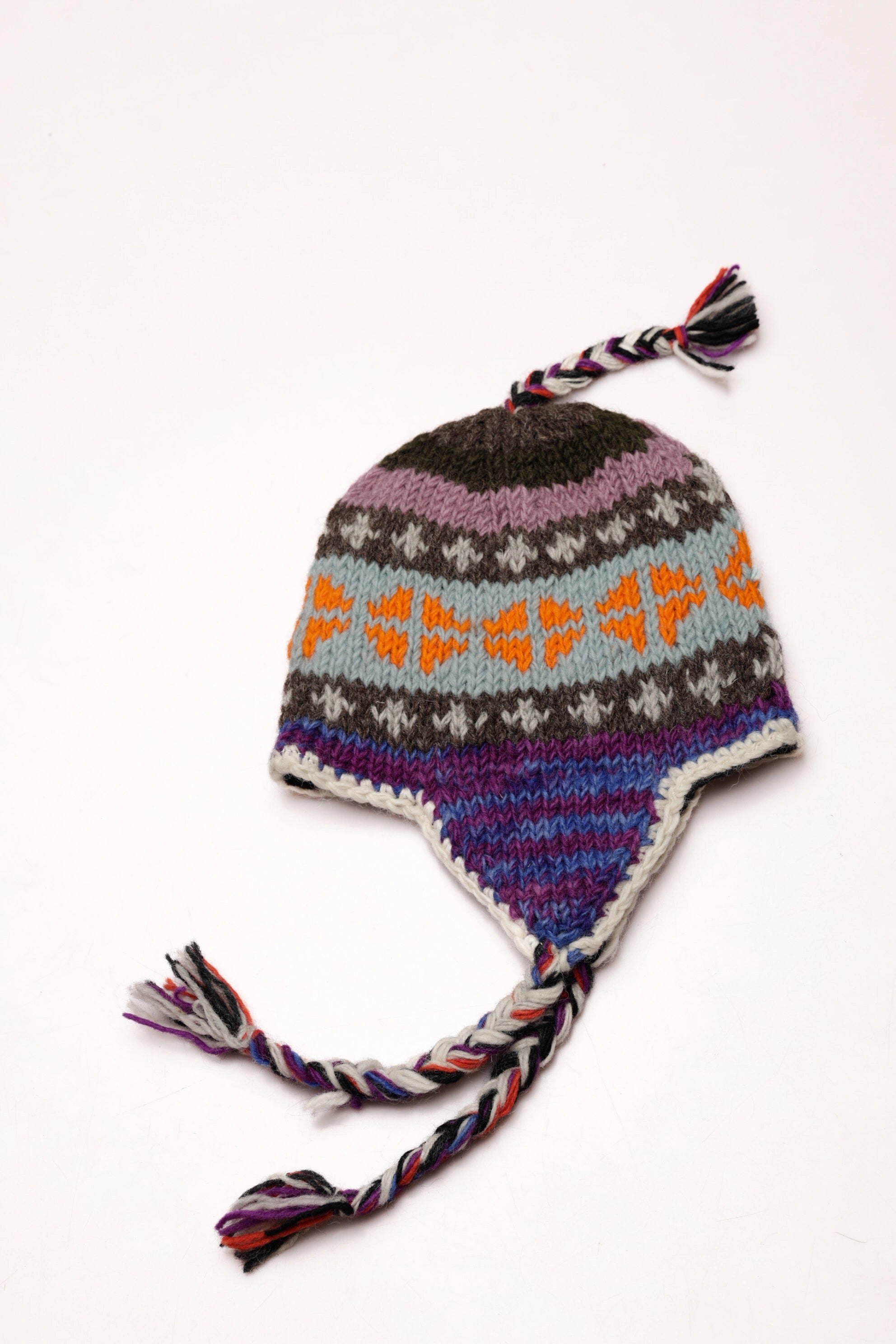 Colorful knitted hat with pattern and tassels on a white background