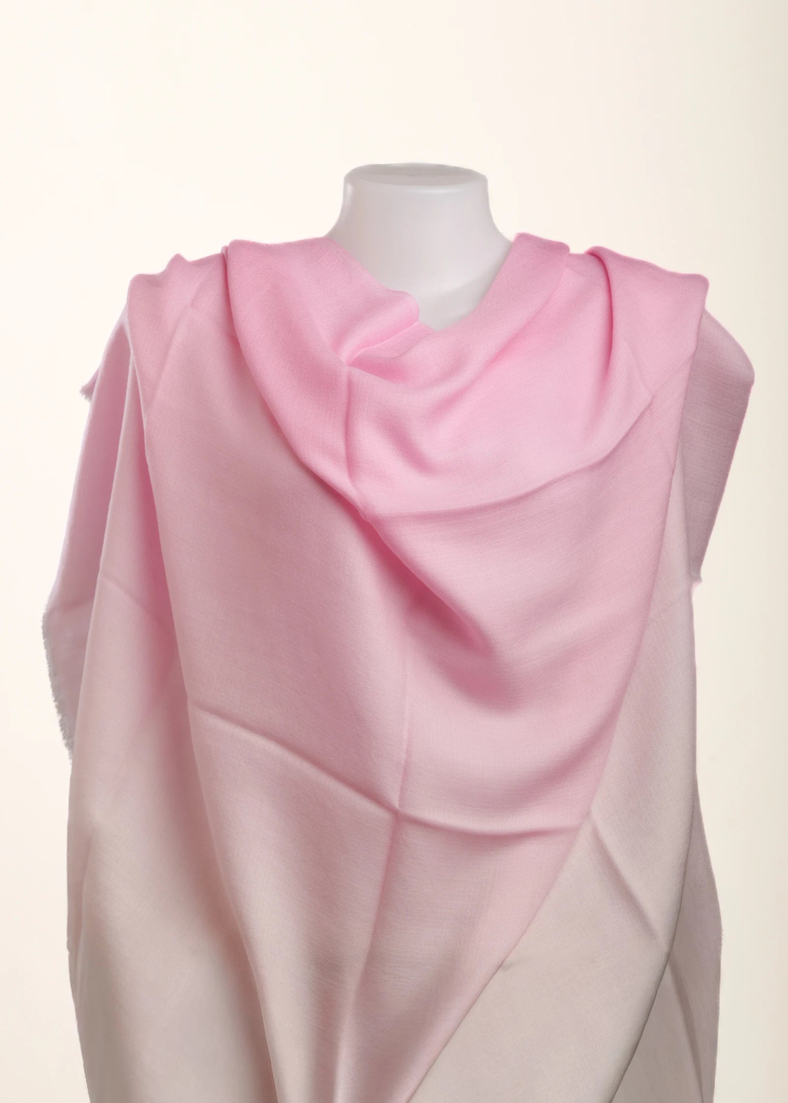 A light pink draped scarf or shawl displayed on a white mannequin torso against a plain off-white background.