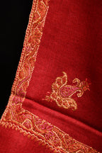 Close-up of a red fabric with intricate gold embroidery on a black background