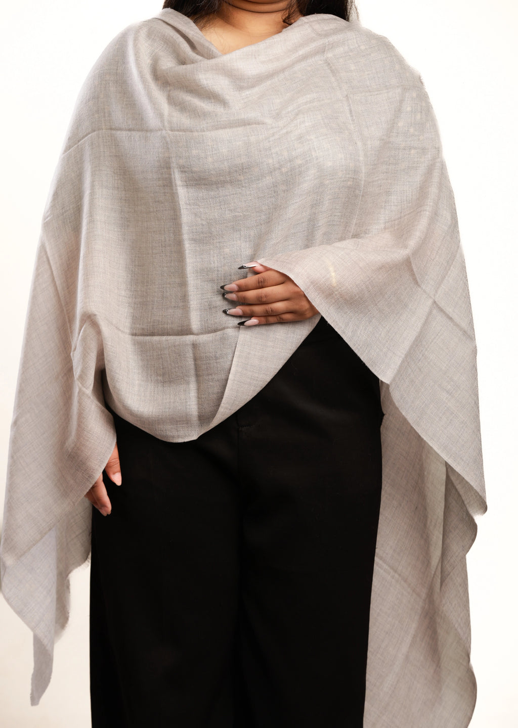 Person wearing a light gray shawl over a plain background