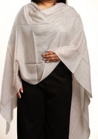 Person wearing a light gray shawl over a plain background