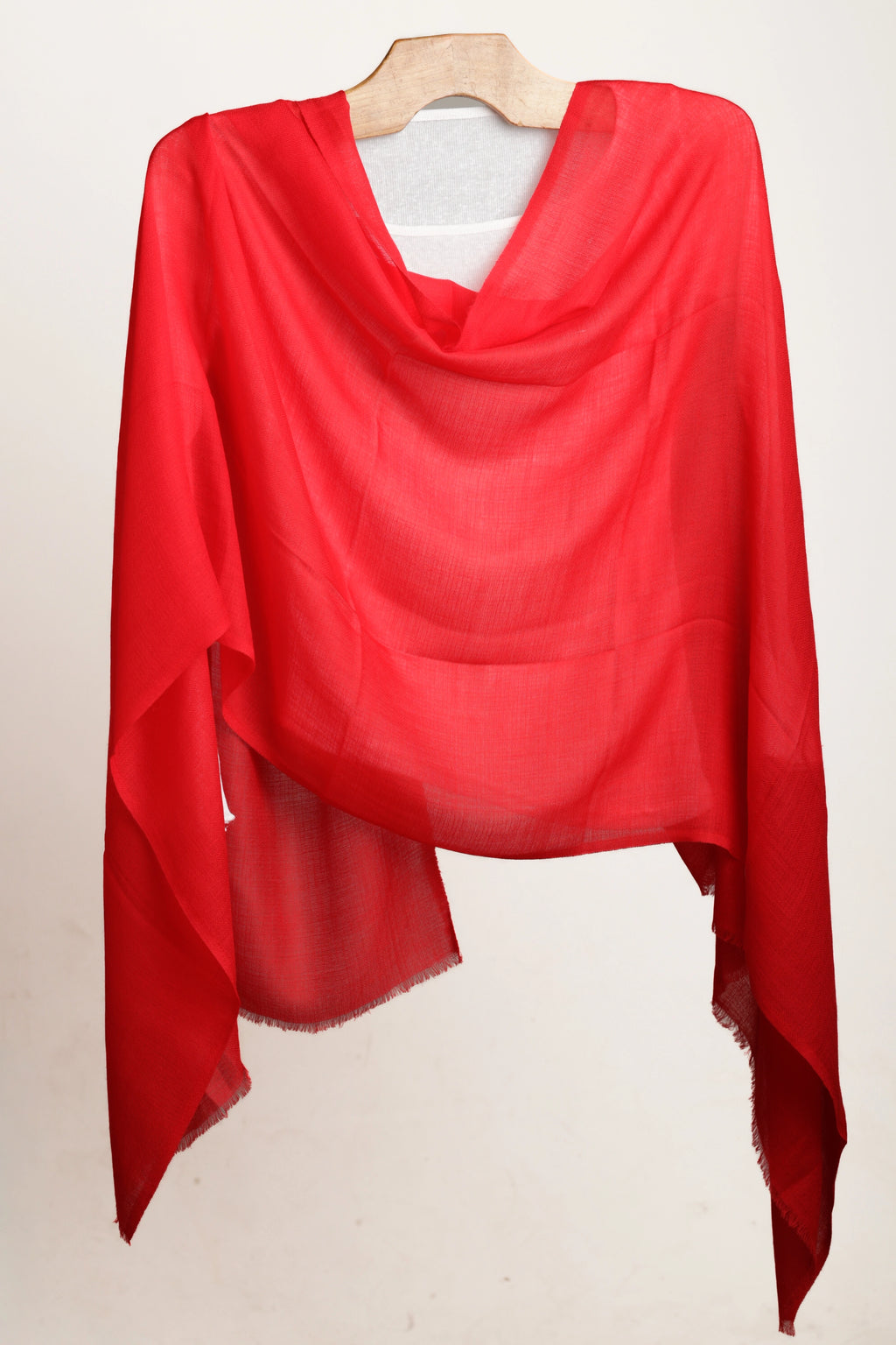 Red scarf draped over a wooden hanger on a white background