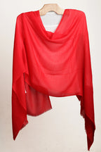 Red scarf draped over a wooden hanger on a white background
