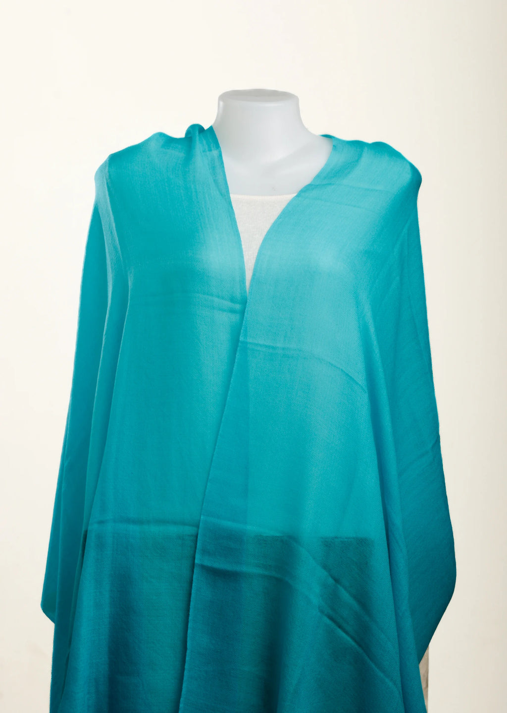 Turquoise poncho on a mannequin against a white background