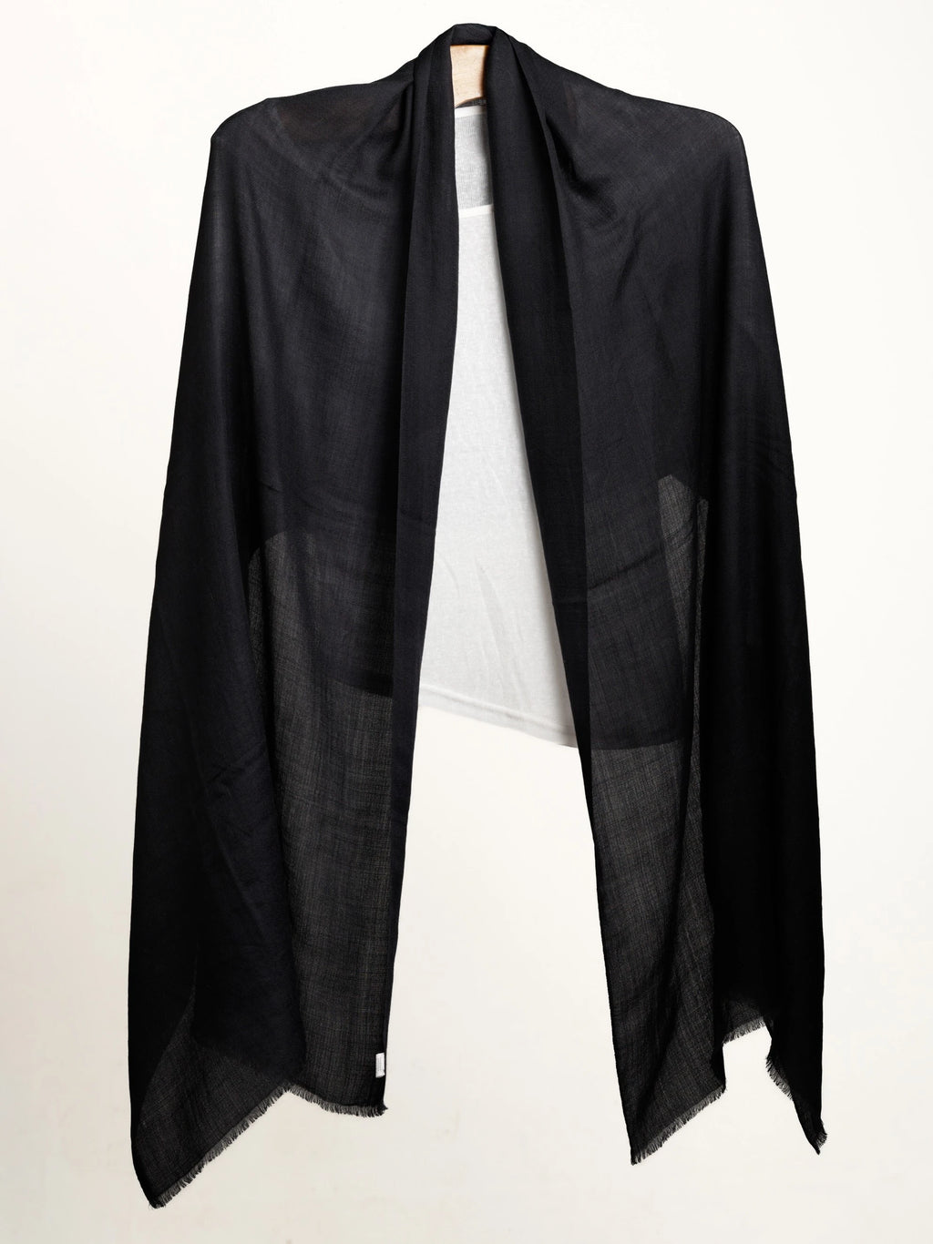 Black shawl layered over white top on a white background