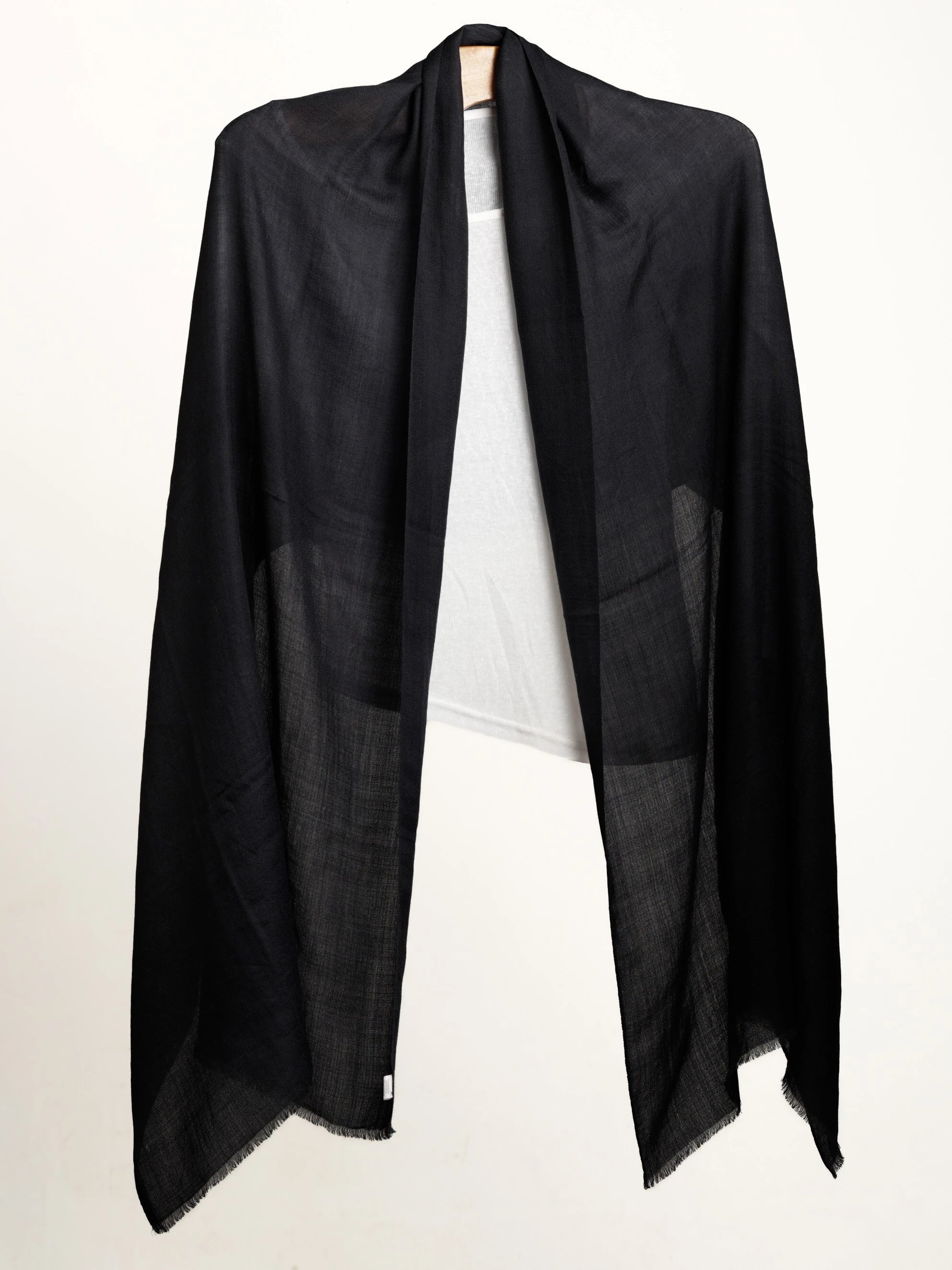 Black shawl layered over white top on a white background