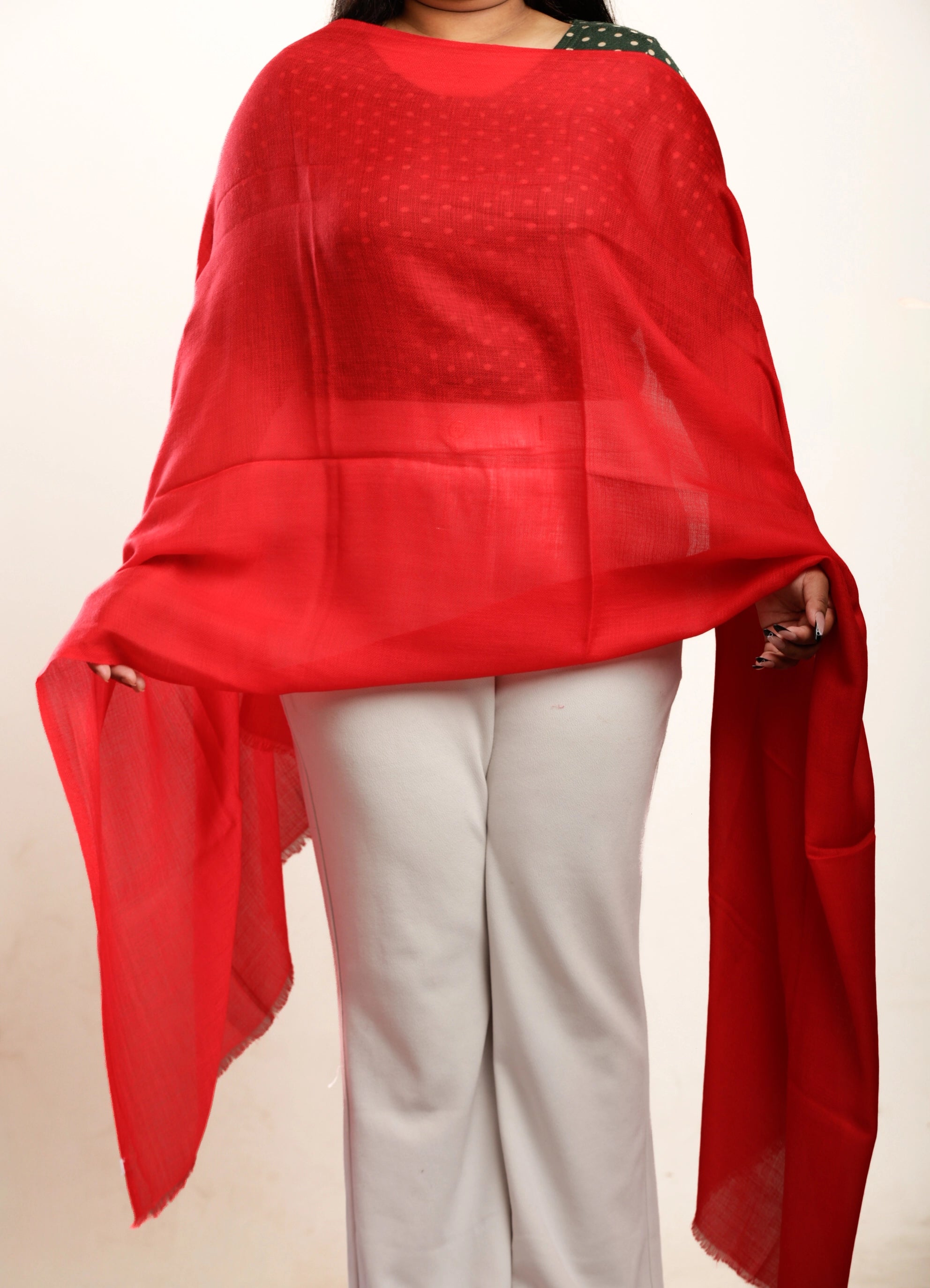 Person wearing a red scarf over shoulders with a plain background