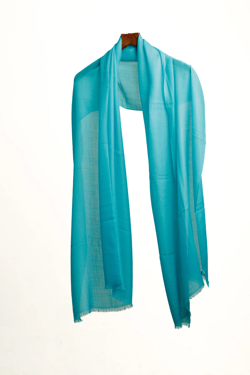 Turquoise scarf draped over a wooden hanger on a white background