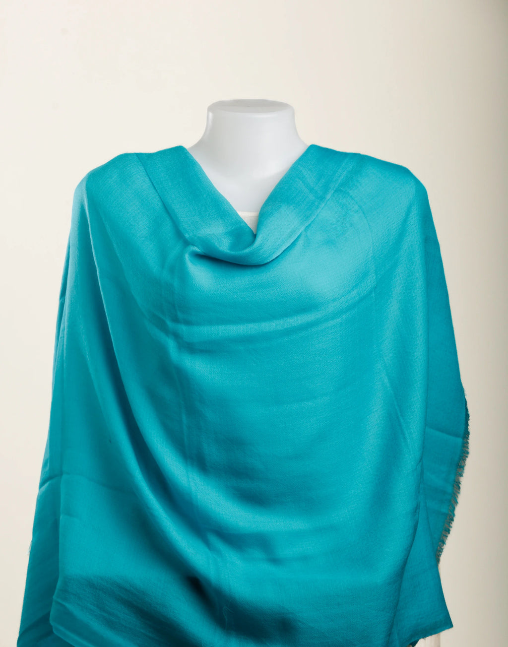 Turquoise scarf draped over a mannequin on a white background