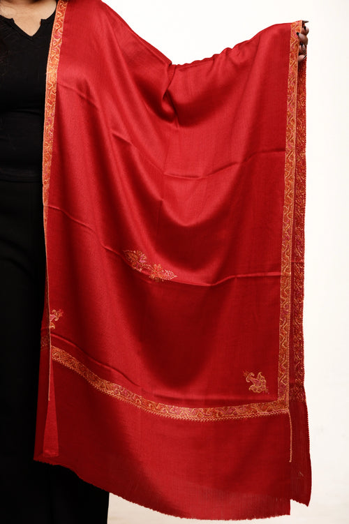 Red scarf with gold border draped over a person on a white background